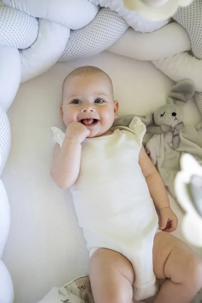 Adorable niña sonriente con un conejito de juguete en la cuna — Foto de Stock