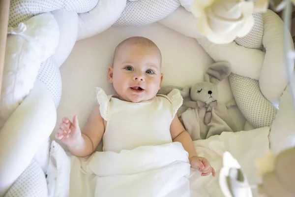 Adorable niña sonriente con un conejito de juguete en la cuna — Foto de Stock