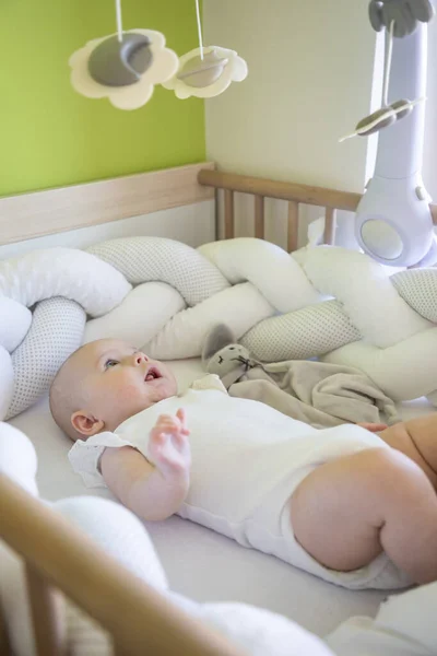 Adorable niña sonriente con un conejito de juguete en la cuna — Foto de Stock