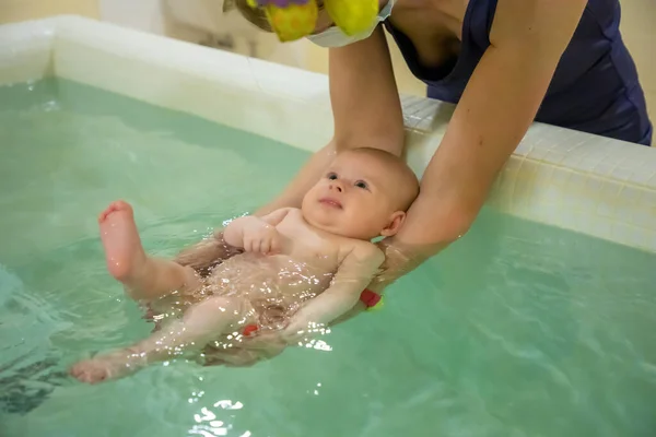 Baby simma på mödrar händer i offentligt bad — Stockfoto