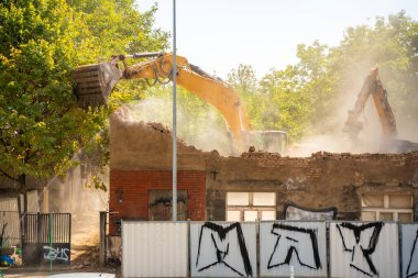 Prag, Çek Cumhuriyeti - 28 Ağustos 2025: Kazıcı bir şehir caddesinde eski bir binayı yıkıyor. Kentsel yeniden yapılanma, yapısal parçalanma ve şehir mimarisinin dönüşümü kavramı. 