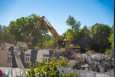 Prag, Çek Cumhuriyeti - 28 Ağustos 2025: Kazıcı bir şehir caddesinde eski bir binayı yıkıyor. Kentsel yeniden yapılanma, yapısal parçalanma ve şehir mimarisinin dönüşümü kavramı. 