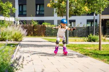 Küçük kız beş yaşında ilk kez paten kaymayı öğreniyor. Aktif oyun yoluyla fiziksel gelişim, denge eğitimi ve çocukluk bağımsızlığı kavramı. Yüksek kalite fotoğraf