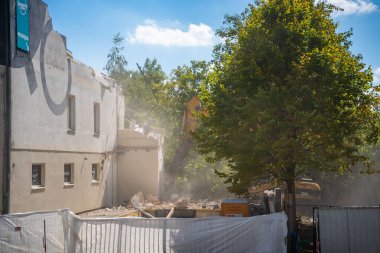 Prag, Çek Cumhuriyeti - 30 Ağustos 2025: Bir şehir caddesinde hidrolik çene ile eski bir binanın parçalarını yıkan yıkım kazıcısı. Yapısal parçalanma ve kentsel yeniden yapılanma kavramı. 