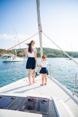 Anne ve kızı yelkenli bir yatın pruvasında birlikte vakit geçiriyorlar. Aile bağları, deniz maceraları ve huzurlu bir seyahat tarzı. Yüksek kalite fotoğraf
