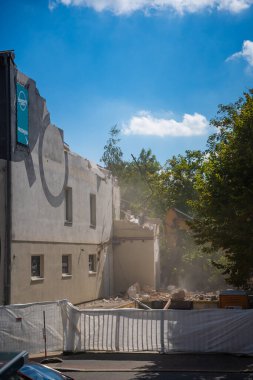Prag, Çek Cumhuriyeti - 30 Ağustos 2025: Bir şehir caddesinde hidrolik çene ile eski bir binanın parçalarını yıkan yıkım kazıcısı. Yapısal parçalanma ve kentsel yeniden yapılanma kavramı. 