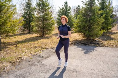 Sabah egzersizi sırasında parkta esneme hareketleri yapan bir kadın. Sağlıklı rutin, vücut hareketliliği ve aktif yaşam tarzı. Yüksek kalite fotoğraf