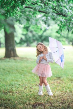 Little girl dancing with her eyes closed while holding an umbrella in the rain. A poetic and expressive moment of childhood joy and freedom. High quality photo