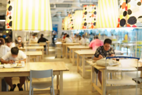 Blurred modern restaurant or cafeteria's interior with clear plastic barriers / dividers on table as part of safety protection for customers. New normal & Social distancing during Covid-19 pandemic