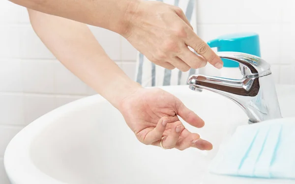 閉じる 人の手を洗うためにタブの水をオンにし ウイルス感染症から保護するために彼の手をきれいにする蛇口ハンドルを引く 自宅のバスルームで洗面所でCovid 19パンデミック — ストック写真