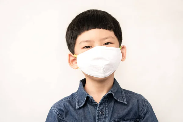 Küçük şirin Asyalı çocuğun portresi günlük hayatta Coronavirus 'u Covid-19 salgınından ve sosyal mesafelerden korumak için tıbbi maske takıyor. Öğrenci konsepti için güvenli & yeni normal