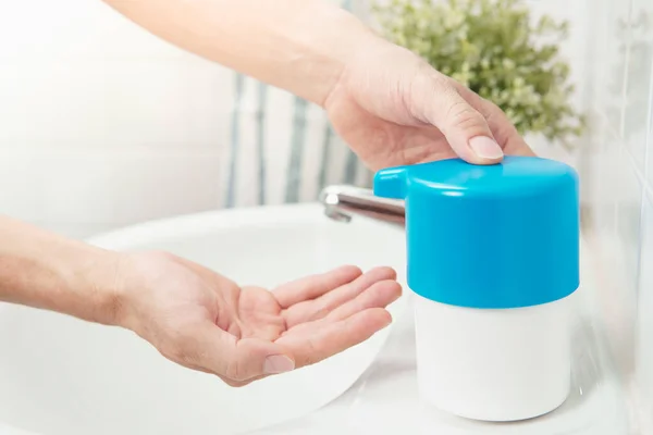 Closeup, Hands of man press pump bottle of 60% alcohol-based hand sanitizer gel / soap to wash and clean his hand to protect from infection of virus outbreak, covid-19 pandemic on wash basin at home.