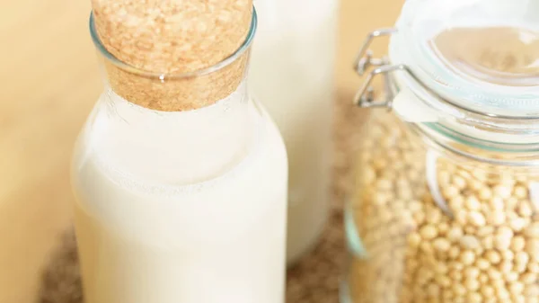 İki şişe taze ve ev yapımı soya sütlü soya fasulyesi dolu cam bir kavanoz. Alternatif sağlıklı süt, laktoz intolerans içeceği, vegan ve bitki temelli diyet konsepti. 