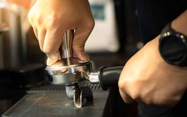 Yakından bakıldığında, barista 'nın sağ eli kahve karıştırıcıyı tutuyor ve espresso makinesiyle demlenmeden önce çift püskürtülü portafilter soldan kavradı. Pratik mükemmelleştirir..