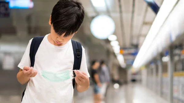 Yeraltı treni platformundaki Asyalı genç çocuk virüs, salgın, hava kirliliği, tehlikeli parçacıklar, 2.5. Başbakan ve salgın hastalıklardan korunmak için tıbbi maske takmaya isteksiz..