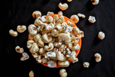 Siyah arka planda izole edilmiş turuncu bir kasede patlamış mısır. Karanlık arka plan. Seçici odak