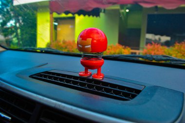 Character Doll on the car dashboard, shake head clipart