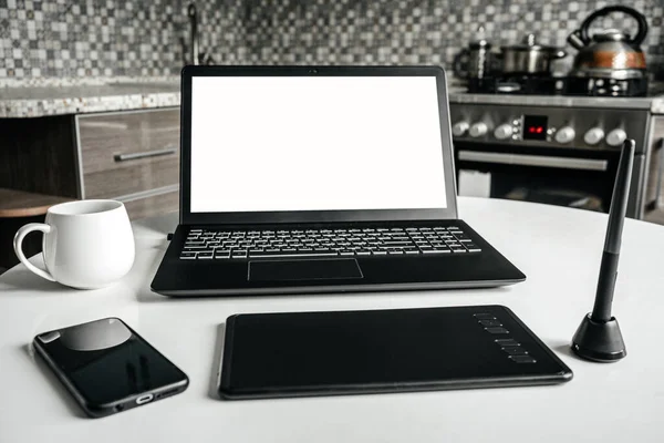 Mutfakta grafik tasarımcı ve mimarın ev işi. Masada dizüstü bilgisayar, grafik tableti ve telefon var. Uzaktan kumanda. Bağımsız