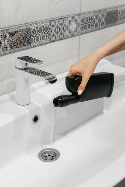 Removal of blockage in the sink, the hand of a woman with a bottle of a special remedy with liquid remedy. Clean the blockages in the bathroom with chemicals. — Stock Image Removal Blockage Sink Hand Woman Bottle Special Remedy Liquid Remedy Stock Photo
