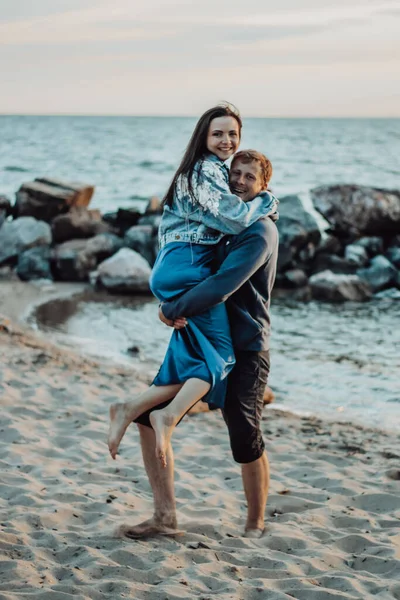 Los amantes se ríen en la playa. El tipo lleva a la chica en sus brazos . —  Fotos de Stock