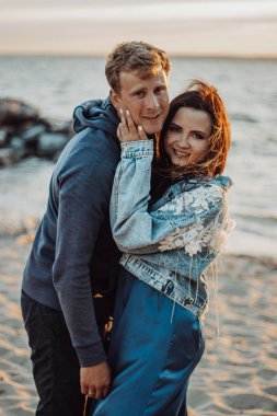  Kumsalda romantik bir yürüyüş yapan, gülümseyen ve sarılan bir çift.
