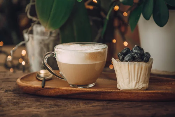 Kaffee mit Milch in einer durchsichtigen Tasse und ein Kuchen mit Beeren. Frühstück in einem Café — Stockfoto