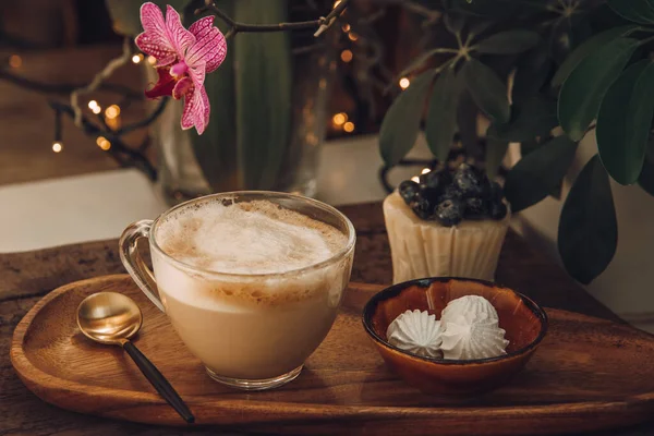 Kaffee mit Milch, Baiser und Kuchen mit Beeren zum Frühstück im Café. Holztisch und Orchidee — Stockfoto