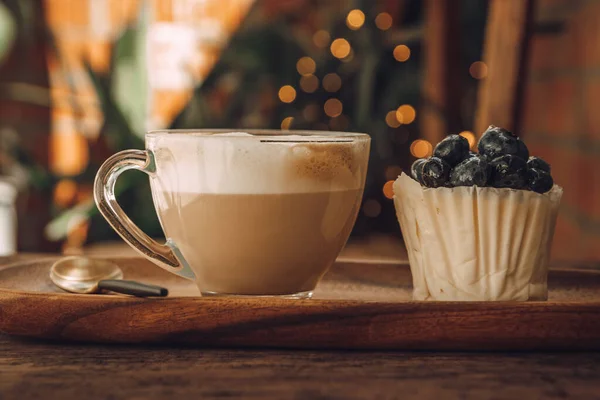 Kaffee mit Milch in einer durchsichtigen Tasse und weißem Cupcake mit Beeren — Stockfoto