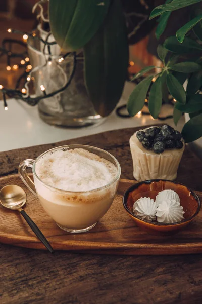 stock image  Cappuccino in a transparent cup, cupcake with berries and meringues on a table in a cafe. Vertical photo