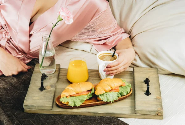 A lány az ágyban reggelizik. Kávé, croissant és narancslé — Stock Fotó