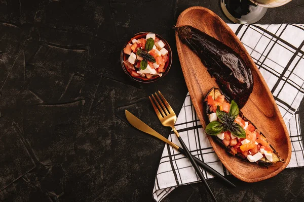 Berenjena al horno con ensalada de tomate, queso feta y albahaca en un plato de madera. Espacio libre para texto — Foto de Stock