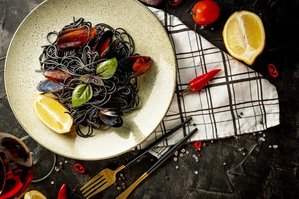 黒パスタ皿に魚介類と黒の背景 — ストック写真