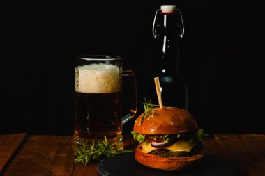  Lezzetli hamburger, ahşap masada bir kupa bira.