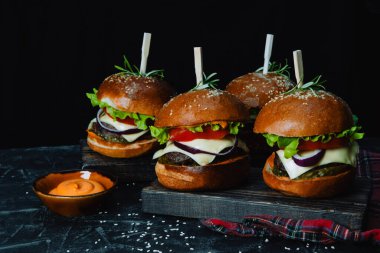 Siyah arka planda bir sürü ev yapımı hamburger.