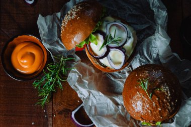  Ahşap bir masada soslu iki ev yapımı hamburger.