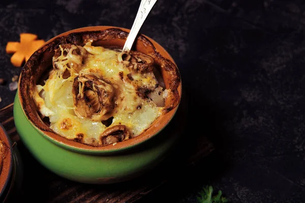 Baked potatoes with mushrooms in a clay pot on a black background. High quality photo — Stock Image Baked Potatoes Mushrooms Clay Pot Black Background High Quality Photo Royalty Free Stock Images