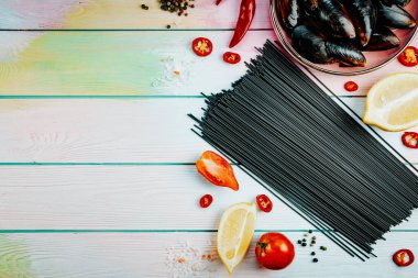  Deniz ürünleriyle makarna yapmak için gerekli malzemeler. Ahşap arka planda siyah spagetti, üst manzara, yazı için boş yer. Yüksek kalite fotoğraf