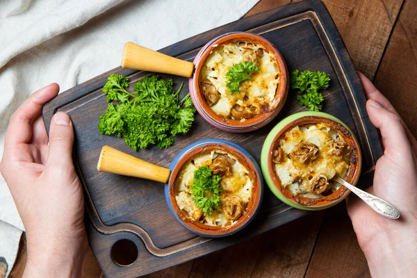 Hands hold a tray with portions of baked julienne. Baked potatoes with mushrooms served to the table. High quality photo — Stock Image Hands Hold Tray Portions Baked Julienne Baked Potatoes Mushrooms Served Royalty Free Stock Images