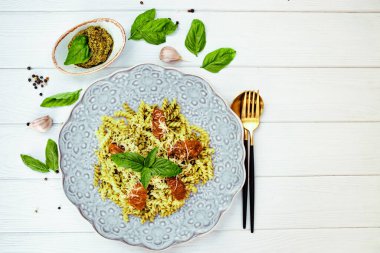 Pesto soslu İtalyan makarnası ve beyaz ahşap arka planda güneşte kurutulmuş domatesler, üst manzara, telif alanı. Yüksek kalite fotoğraf