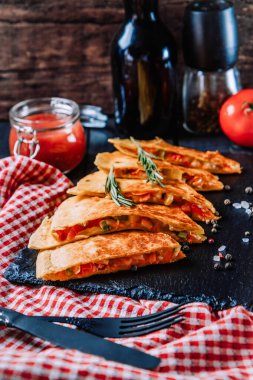 Siyah tabakta Meksika quesadilla 'sı, yakın plan, dikey fotoğraf. Yüksek kalite fotoğraf