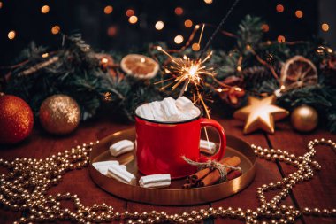 Yeni yıl ortamında marşmelovlu bir fincan kakao ve yanan bir maytap. Yüksek kalite fotoğraf