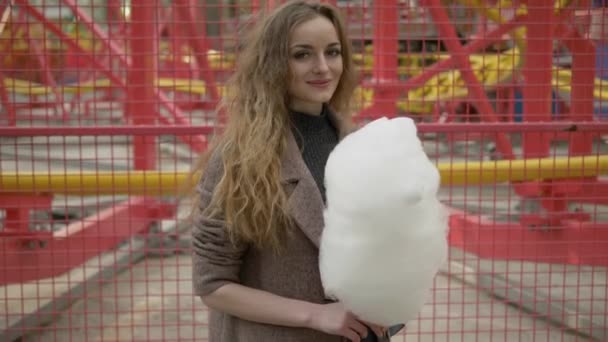 Medium Shot Of Young Adorable Long Hair Curly Blonde Woman In Trendy Coat Enjoying Candy Floss In City Park
