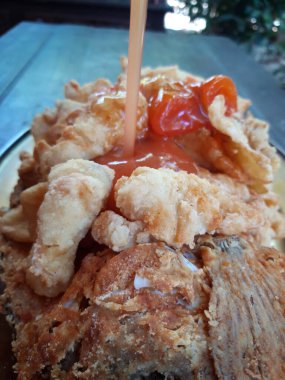 Domates sosu masadaki bir tabakta gevrek yiyeceğe dökülür.