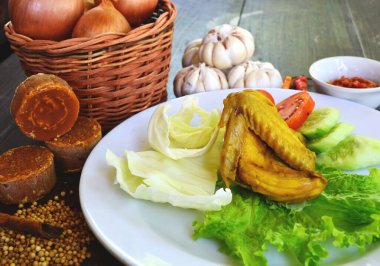 Endonezya 'dan lezzetli yemekler servis ediliyor. Baharat ve bitkilerin arka planında taze sebzeli kızarmış tavuk.