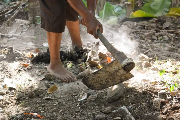 Çöp toplayıcı kuru temizleme leğeni ve gün boyunca avluda çapa kullanarak toprağı düzleştiriyor.