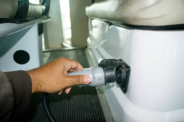 Eller elektrikli bir arabayı şarj etmek için kabloyla elektrik prizi tutuyor. Ulaştırma Teknolojisi Konsepti