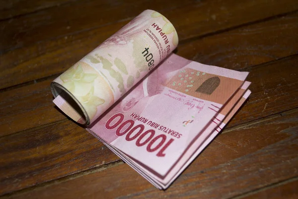 Endonezya rupia banknotları ahşap üzerine yuvarlanmış.