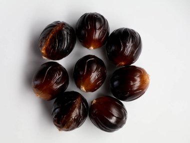 Beyaz arka planda tutulan taze kahverengi hindistan cevizi tohumu. Nutmeg, Myristica parfümleri, baharatlı meyveleri olan tropikal bir yeşil ağaçtır.