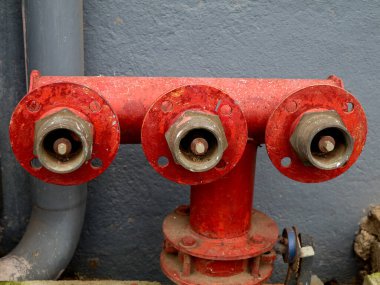 Duvarın altındaki kırmızı yangın söndürme vanaları, güvenlik kavramı.