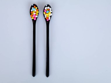 Çok renkli rezene şekeri siyah kaşıklarda beyaz arka planda fotokopi alanı ile izole edilmiş.